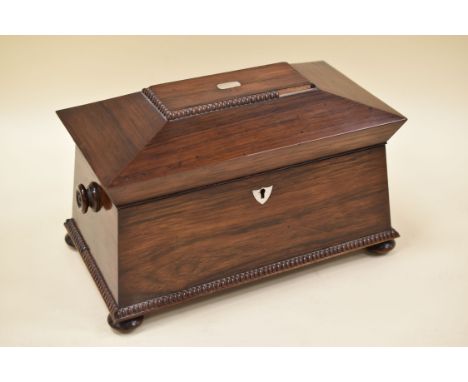 A ROSEWOOD TEA-CADDY of sarcophagus form on four bun feet, beading decorated with mother-of-pearl detail and turned twin-hand