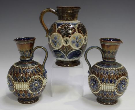 A pair of Royal Doulton stoneware jugs, decorated by Ethel Beard, monogrammed, with relief stylized foliate medallions within