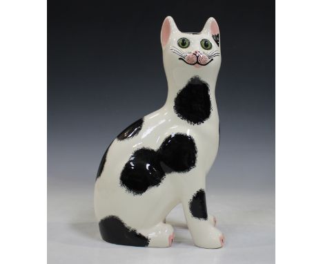 A large Griselda Hill Pottery Wemyss style cat, modelled seated with black patch detail, inset with glass eyes, black painted