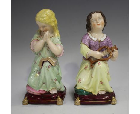 A pair of Stevenson &amp; Hancock Derby porcelain figures, late 19th century, each modelled as a kneeling girl on a gilt tass