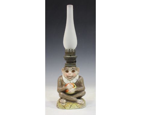 A Continental porcelain oil lamp base, late 19th/early 20th century, modelled in the form of a monkey holding a fruit, inset 
