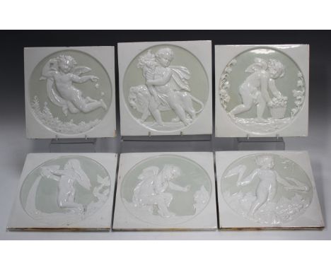 A set of six relief decorated cream glazed square tiles, circa 1900, each with a circular panel depicting a cupid, putto or n