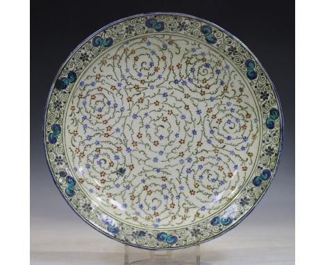A Doulton Lambeth Persian Ware pottery circular dish, 1920s, painted with spirals of green foliage punctuated with red and bl
