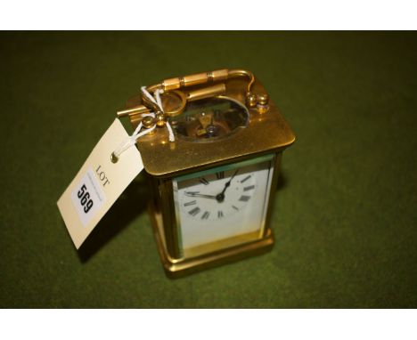 A brass carriage clock with white enamel face.