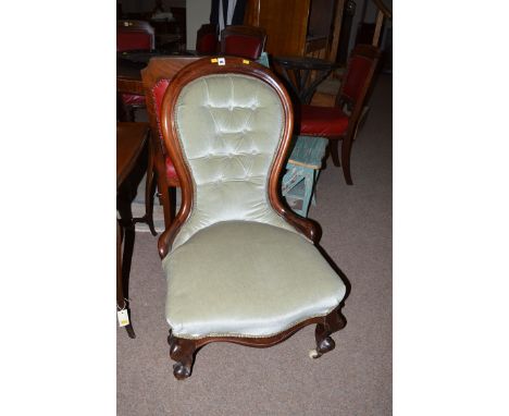 A Victorian nursing chair, the buttoned back and seat upholstered in green velour, raised on scrolling legs terminating in ce