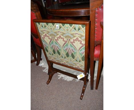 A 20th Century mahogany firescreen, the glazed panel inset with printed Liberty material, 76cms high.