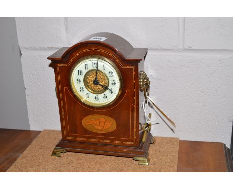 An Edwardian inlaid mahogany mantel clock with enamel arabic dial, lion mask ring handles and shell paterae, 22cms high.