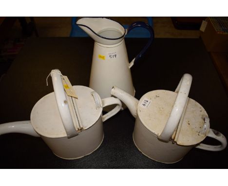 Two white enamel watering cans; together with a white enamel jug with blue handle.
