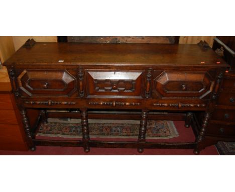 A Jacobean style joined and geometric moulded oak three drawer dresser base, raised on bobbin turned and square cut supports 