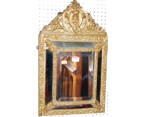 A circa 1900 Italian heavily gilt floral embossed framed bevelled wall mirror, having outer mirrored panels (one panel with d