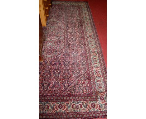 A Persian red ground woollen Tabriz rug, having all-over heavy floral ground to trailing tramline borders, 300 x 192cm.In goo