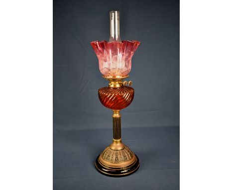 A Victorian brass oil lamp having brass column base, ruby glass font &amp; floral etched shade, overall height 28in. (71 cm.)