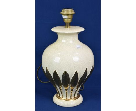 A cream and gold table lamp with leaf pattern. 