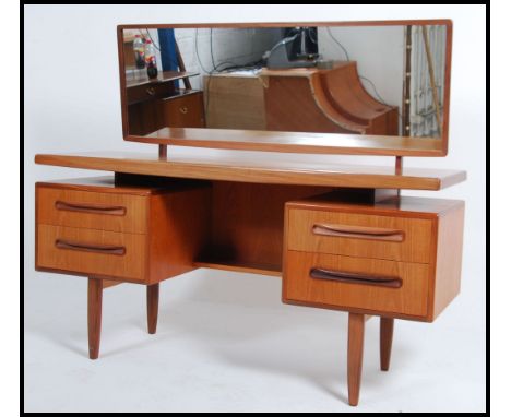 A 1970's retro teak wood G-Plan suspension set dressing table having pedestals of drawers raised over tapered supports with l