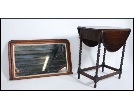 An early 20th century oak gate leg drop leaf table raised on barley twist supports together with an over mantle mirror with a