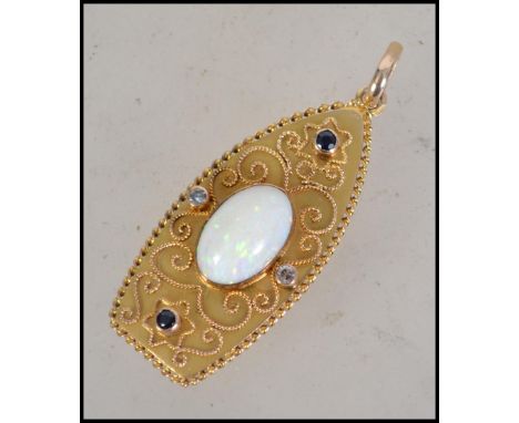 An unusual 18ct gold opal, sapphire and diamond necklace pendant adorned with filigree work to the lozenge shaped back. Centr