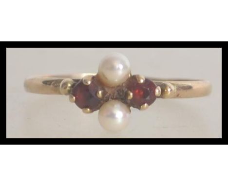 A 9ct / 375 gold ruby garnet stone and seed pearl ladies ring. The ring with twin seed pearls interspersed by 2 round cut rub