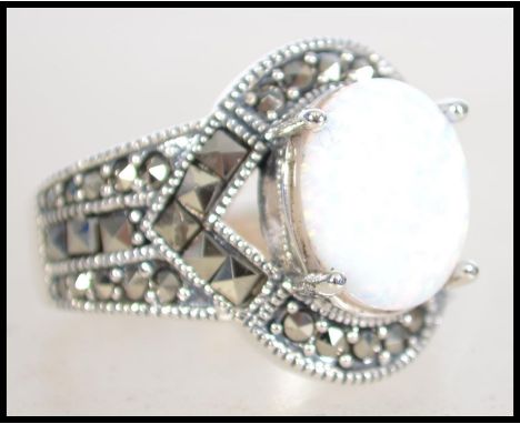 A ladies 20th century Art Deco style silver, marcasite and opal dress ring. The ring with central opal cabochon stone. Size Q