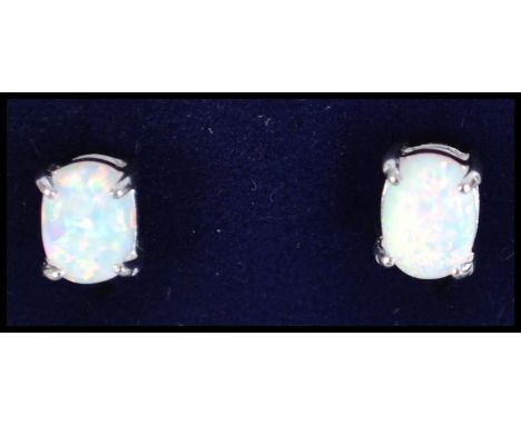 A pair of ladies silver and opal stud earrings, each having claw mounted stones complete in the presentation case