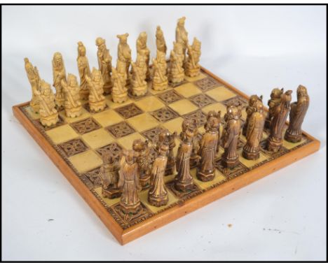 A 20th century Oriental resin chess set complete with heavy tile board with white blank squares and Celtic knot squares havin