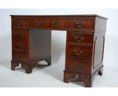A mahogany Georgian style twin pedestal, gilt tooled green leather top over three frieze and six lower drawers, all with bras