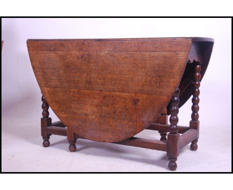 A 19th century carved country oak gate leg - drop leaf dining table raised on bobbin turned legs with oval drop leaves raised