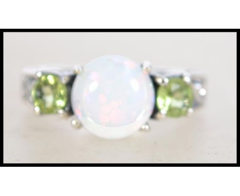 A ladies 20th century silver peridot and opal three stone ring. The central round opal with peridot set shoulders. Size N. We