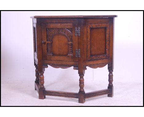 An Ercol oak 'Colonial ' hall cabinet raised on block and turned legs united by stretchers having carved single door to the s