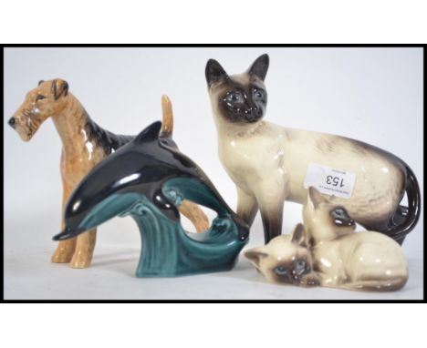 A collection of Beswick figurines to include a dog, large siamese cat, small group of siamese cats and a poole pottery dolphi