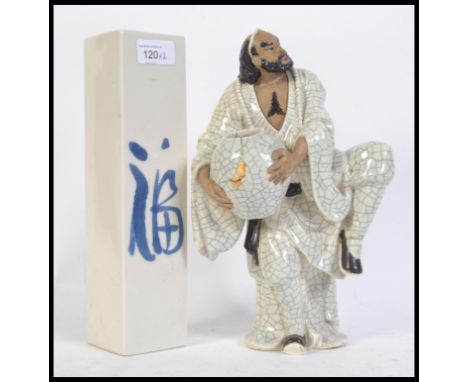 A late 19th century / early 20th century crackle glaze Japanese ceramic figure of a man raised on one leg supporting a bowl t
