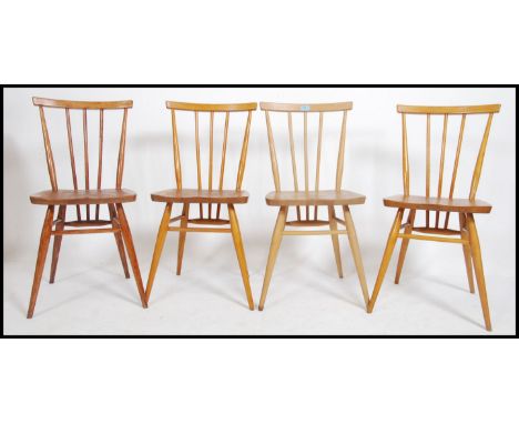 A set of 4 20th century retro Ercol spindle back dining chairs raised on turned legs with upper peripheral stretchers having 