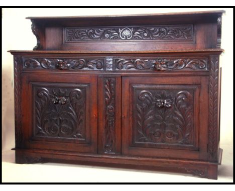 A large 19th century carved oak sideboard buffet having profusely carved doors with short drawers above having green man carv