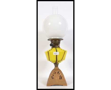 An early 20th century oil lamp with brass burner, the wick winder buttons each marked T.R.S. Raised on a gilt cast base adorn