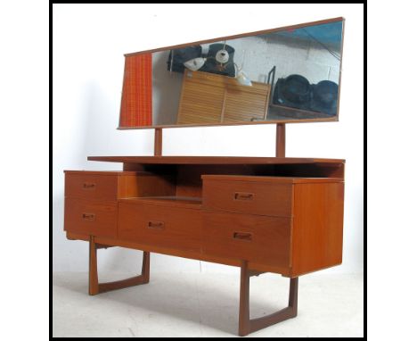 A good 1970's Danish inspired teak wood dressing table being raised on tapering supports having a series of drawers flanking 