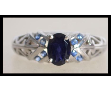 A hallmarked 9ct white gold ring set with central oval cut blue stone with split Celtic style shoulders. Hallmarked Birmingha