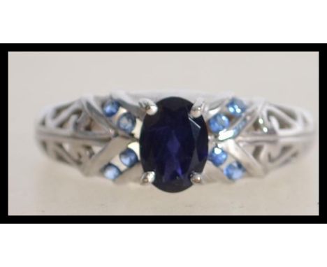 A hallmarked 9ct white gold ring set with central oval cut blue stone with split Celtic style shoulders. Hallmarked Birmingha