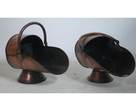 2 Victorian 19th century copper coal scuttles of helmet form, each with shaped hoop carry handles and raised on circular base