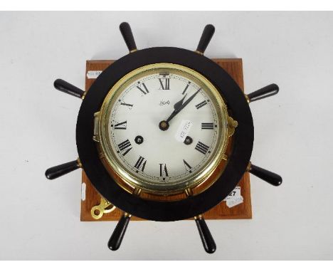 A Schatz brass bulkhead clock with ship's wheel surround.
