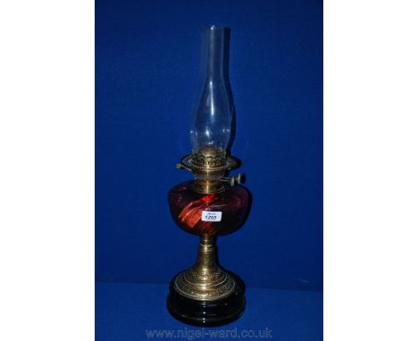 An Oil Lamp with brass column and burner, cranberry glass reservoir and a clear chimney.