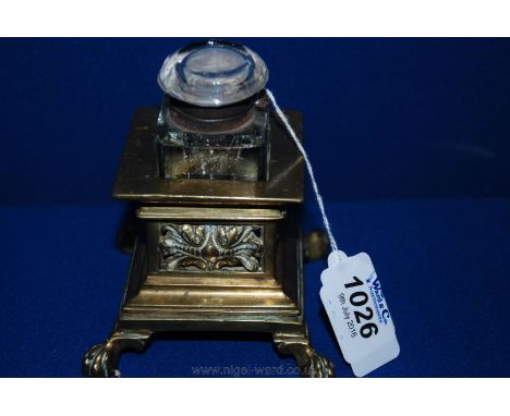 A small glass Inkwell with white metal collar set in a brass holder with fretwork design and ball and claw feet.