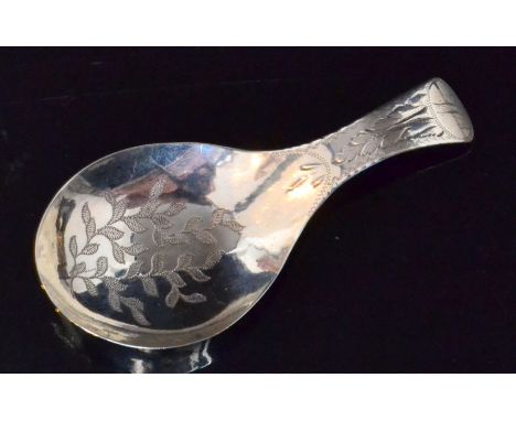 A George III hallmarked silver caddy spoon, oval bowl with bright cut engraved leaf decoration below similar scroll handle wi