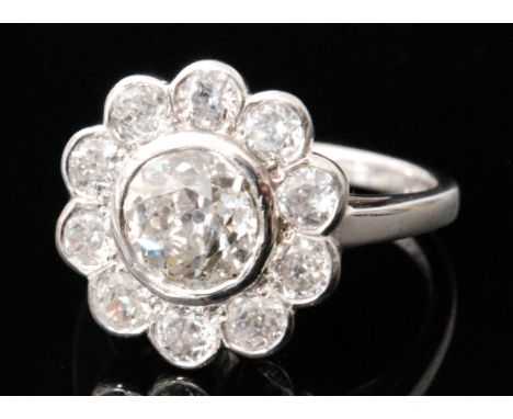 An 18ct hallmarked white gold diamond daisy cluster ring, central brilliant cut stone weight 1.50ct within a ten stone, colla