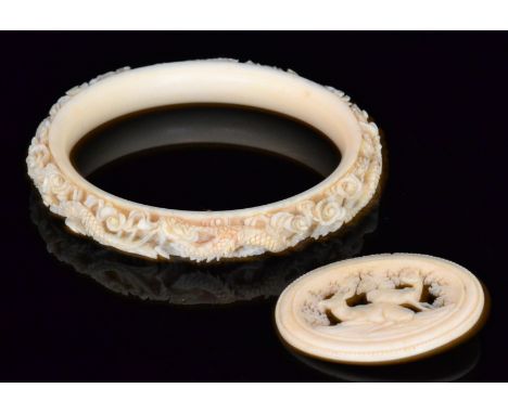 A late 19th to early 20th Century carved ivory bangle, detailed with a repeat pattern of dragons diameter 10cm, together with