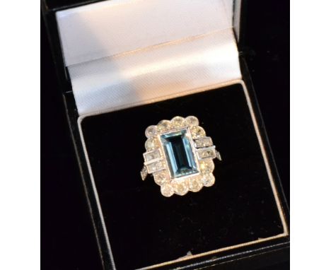 An 18ct white gold aquamarine and diamond cluster ring, central emerald cut aquamarine 3.5ct within brilliant cut diamond sha