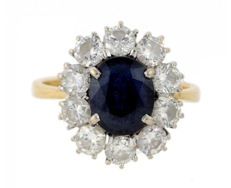 A SAPPHIRE AND DIAMOND RING  London 1981, the oval sapphire in a surround of ten evenly sized round brilliant cut diamonds, i