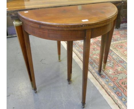 AN EDWARDIAN MAHOGANY AND BROKEN LINE INLAID SEMI CIRCULAR CARD TABLE, ON THREE SQUARE TAPERED LEGS WITH POTTERY CASTORS