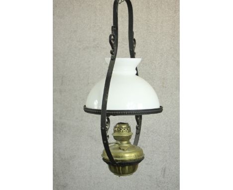 A 19th century colonial style wrought iron and brass hanging oil lamp with an opaline glass shade. H.73 Dia.29.5cm. 
