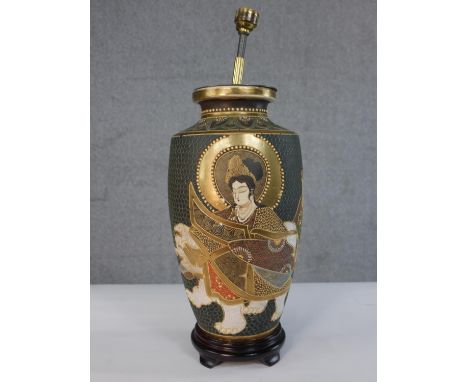 An early 20th century Japanese Satsuma pottery table lamp, decorated with typical figures and gilded detail on a wooden base.
