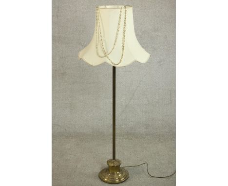 A 20th century standard lamp with a circular brass base and a white shade. H.147 Dia.59cm. 