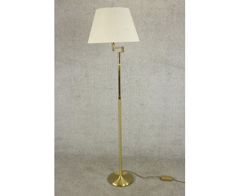A contemporary brass reading lamp, with an adjustable arm on a cylindrical stem with a circular base and a white shade. H.168